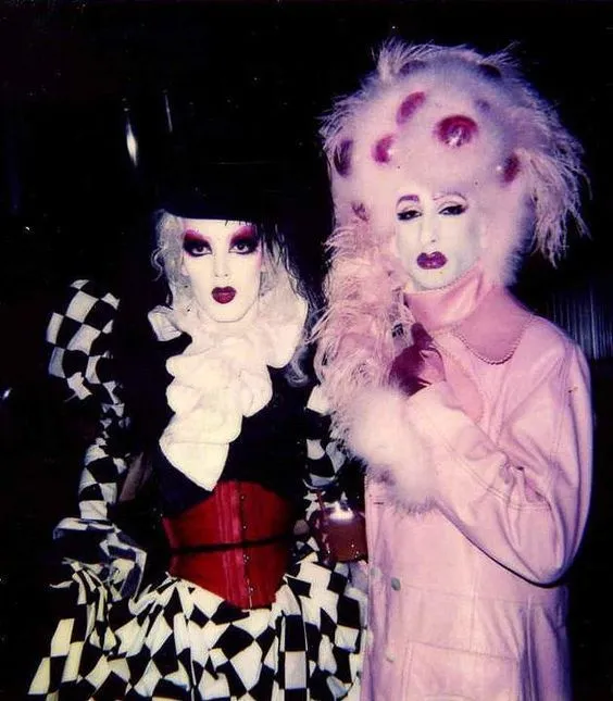 Club Kids aesthetic — The dramatic makeup, avant-garde wigs, and theatrical, constructed garments are a direct visual representation of the Club Kids' performance art dressing.
