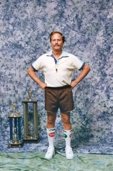 Dadcore aesthetic — The tucked-in polo, athletic shorts, white tube socks pulled high, and the overall 'coach' vibe perfectly capture the reclaimed suburban dad aesthetic, especially with the whistle.