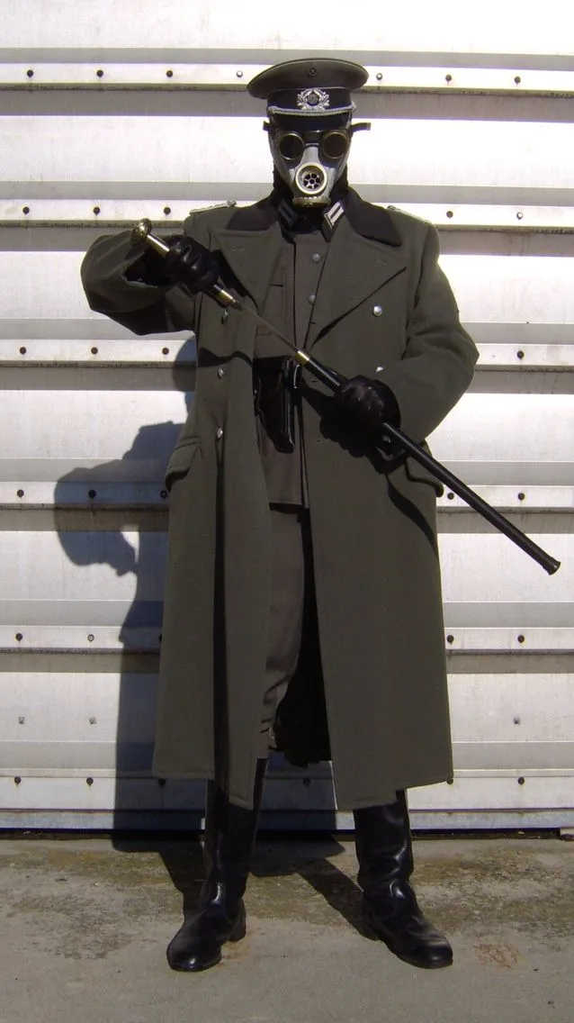 Dieselpunk aesthetic — The military-style wool coat, gas mask, and cap are direct references to the description's militaristic and gas mask iconography.