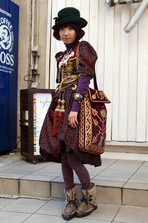 Dolly Kei aesthetic — This image perfectly captures the Dolly Kei aesthetic with its layered folk-print skirt, tapestry waistcoat, religious medallions, antique chains, and muted, rich palette.