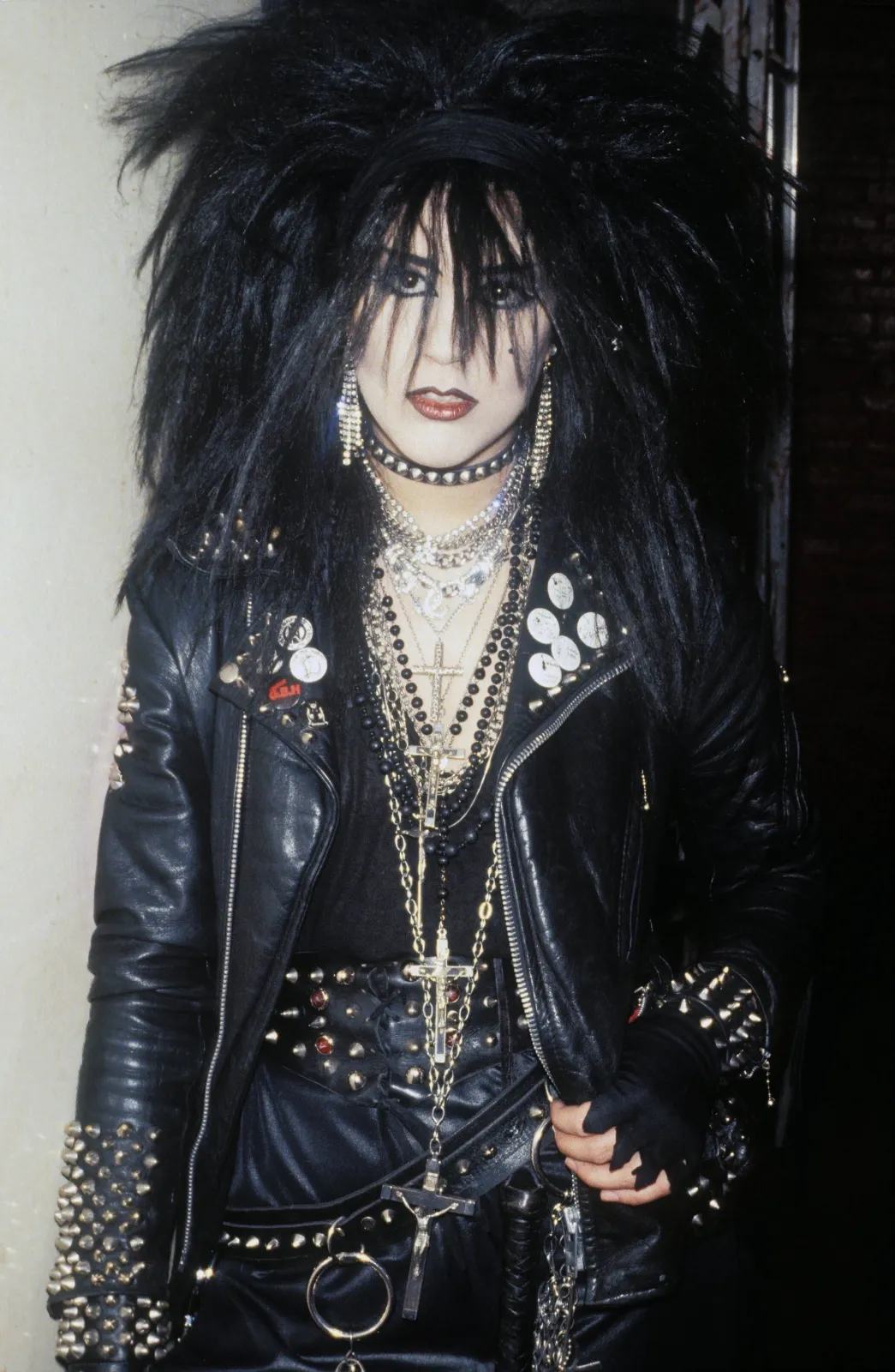 Goth Punk aesthetic — Perfectly captures the aesthetic with a hand-painted leather jacket, multiple crucifixes, spiked accessories, layered jewellery, and the characteristic hair and makeup.