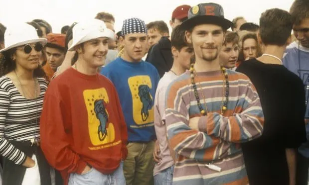 Madchester aesthetic — The fishing bucket hats, tie-dye, and graphic long-sleeves are direct references to the Madchester scene.