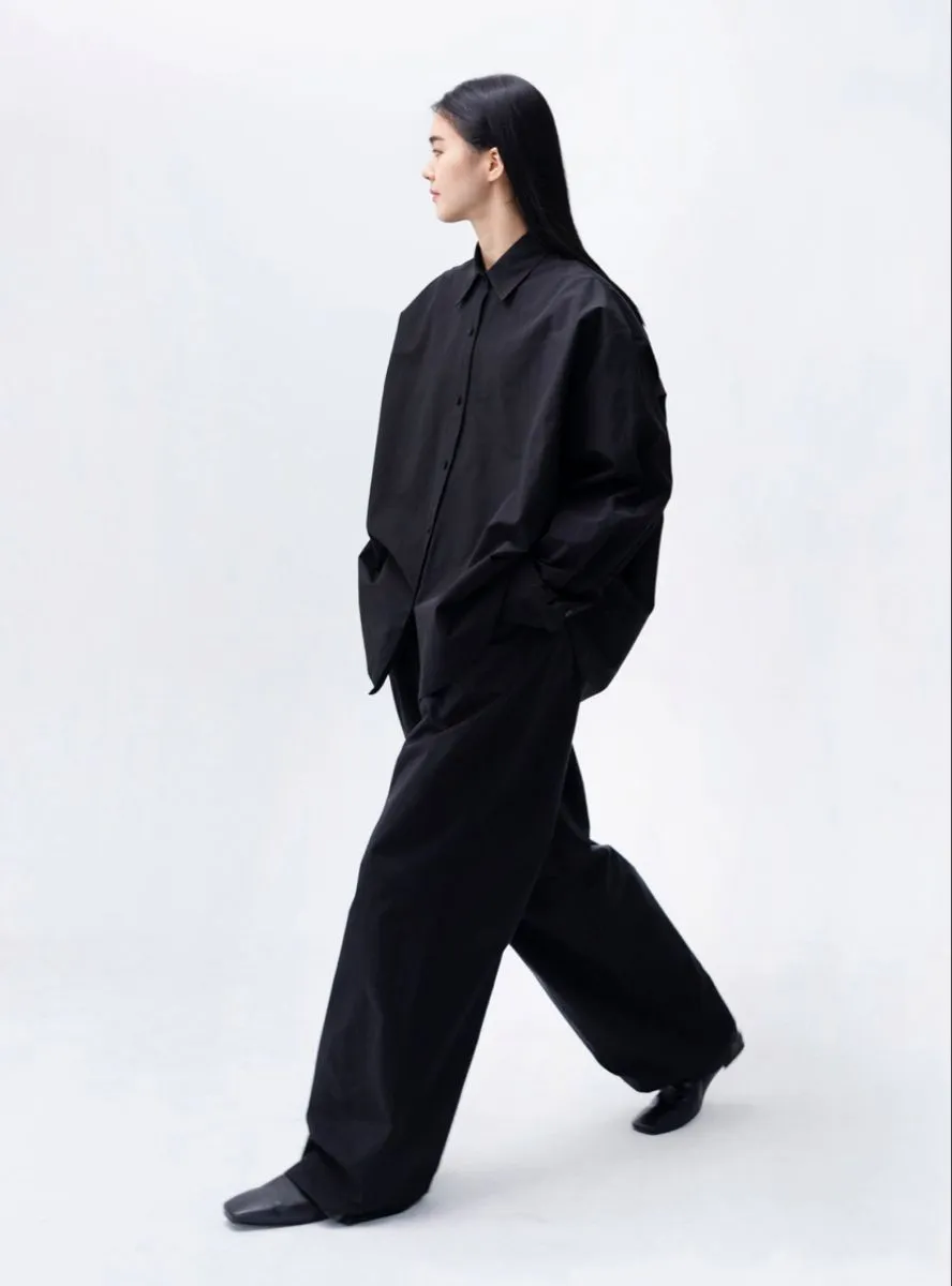 Minimalist aesthetic — The all-black, oversized, flowing silhouette with clean lines and no ornamentation perfectly embodies the minimalist aesthetic, reminiscent of brands like The Row or Jil Sander.