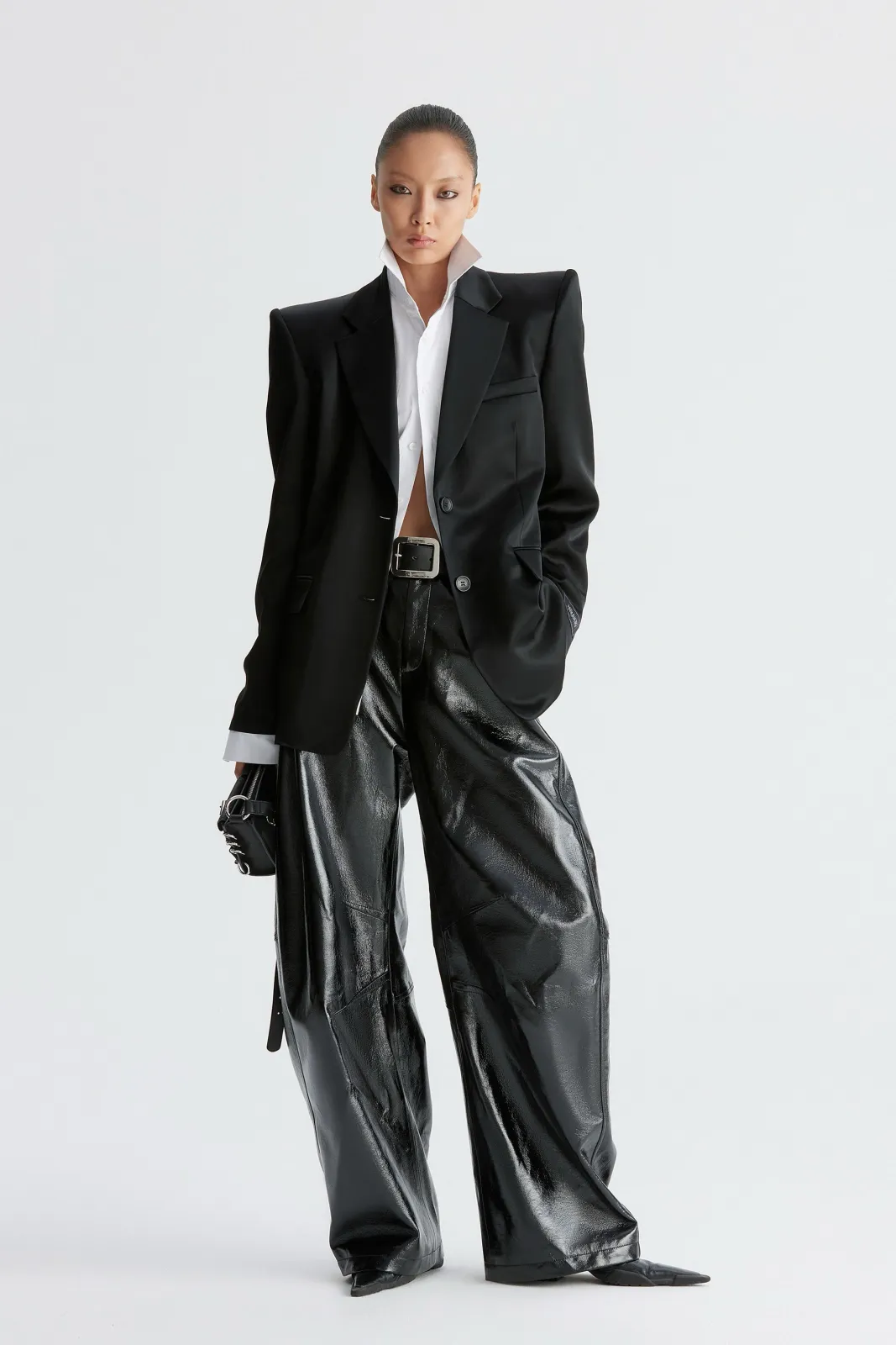 Monochrome Luxe aesthetic — Strict black and white outfit featuring a tailored blazer, patent leather pants, and a crisp shirt, embodying the high-contrast tonal dressing and texture layering.