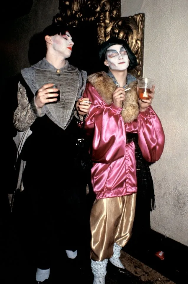 New Romantic aesthetic — This image perfectly captures the theatricality, gender-fluidity, historical drag, and specific visual cues like makeup, satin, and historical silhouettes of the Blitz club scene.