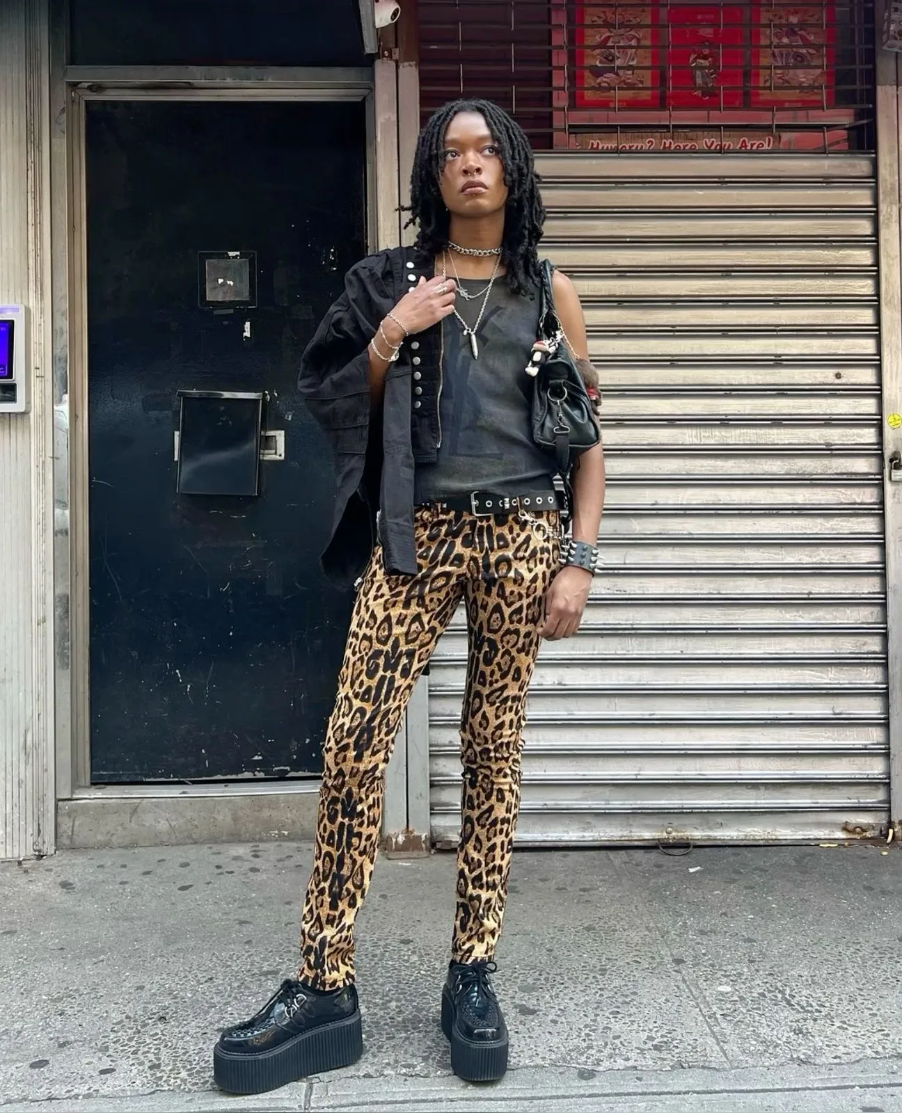 Psychobilly aesthetic — The leopard print pants, platform creepers, studded belt, and sleeveless vest are all strong visual cues for the psychobilly aesthetic.